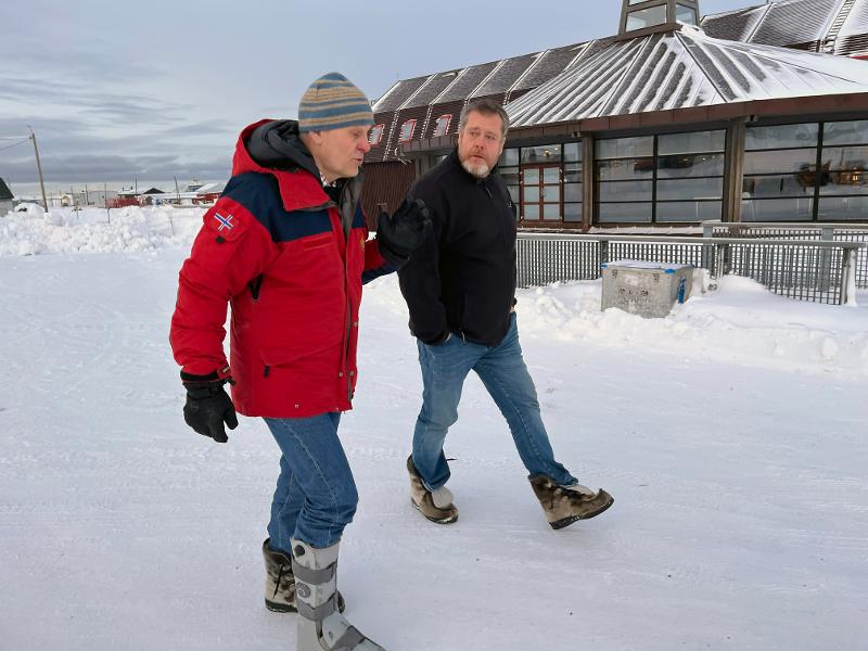 Two persons walking in a icey street.